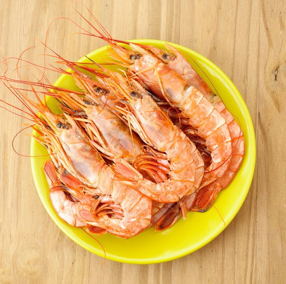 plate of raw prawns on wooden base
