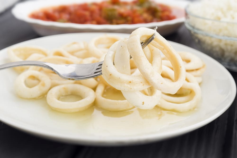 fork picking squid rings a plate on black
